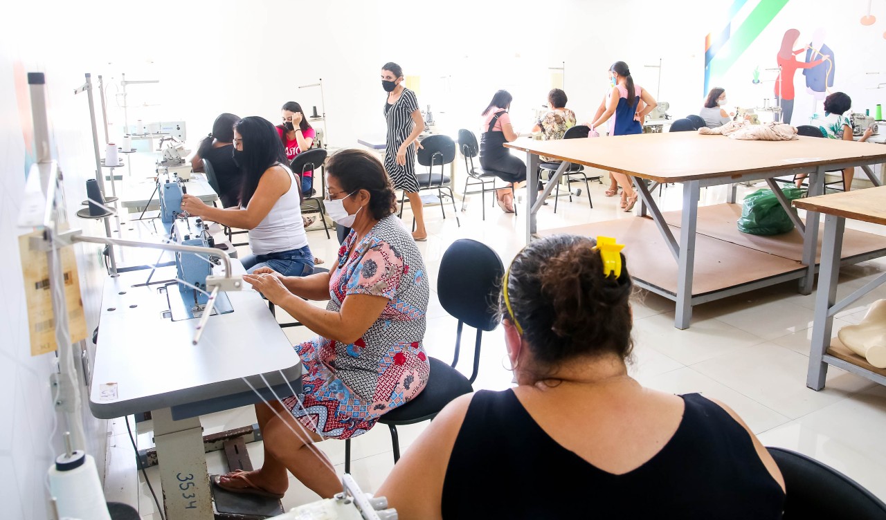 a foto mostra uma sala com máquinas de cosutra e costureiras